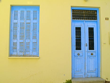 blue door and window shutter of yellow house