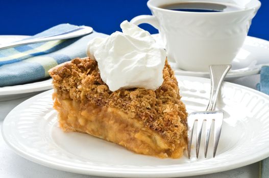 Slice of apple pie with crumble topping and whipped cream.