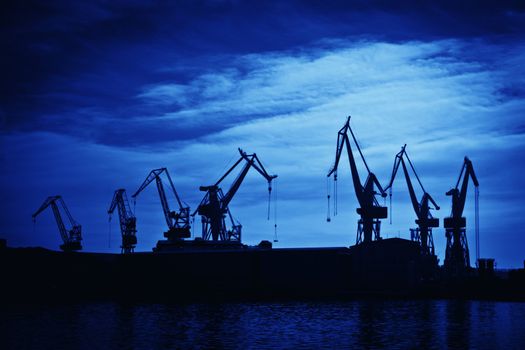 Shipyard cranes against blue sky, artistic toned photo