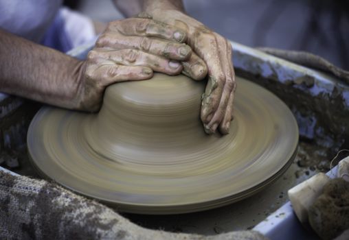 Hands working on pottery wheel , close up retro style toned photo wit shallow DOF