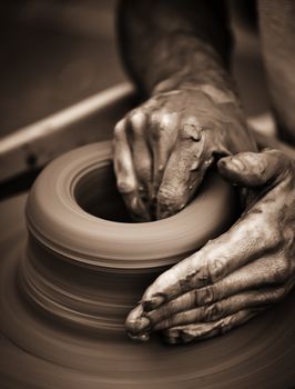 Hands working on pottery wheel , close up retro style toned photo wit shallow DOF