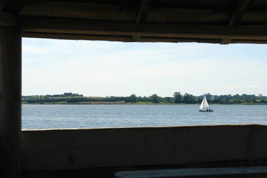 Seascape sea ocean view with a sailing yacht from a wooden seaside cabin                               