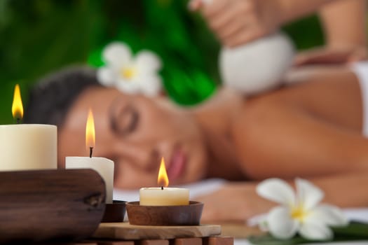 portrait of young beautiful woman in spa environment. Focused on candles.