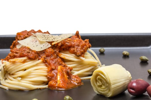 Spaghetti bolognaise in black plate with olives