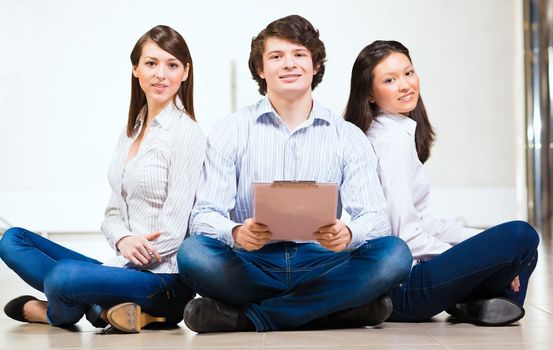 portrait of a group of young people sitting on the floor, man and two attractive women