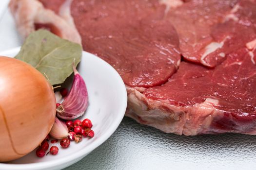 Beef steak with bowl of spices beside for cooking