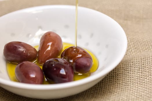 Olives in olive oil in white bowl