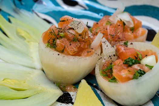 Salmon tartar in onion cups with season vegetables