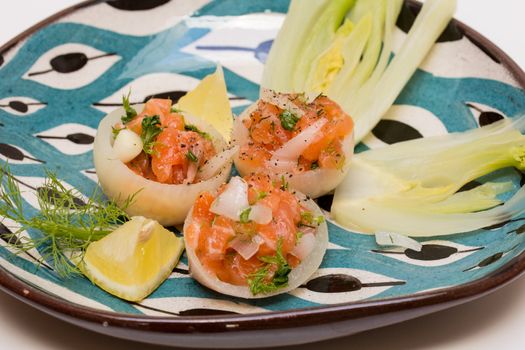 Salmon tartar in onion cups with season vegetables