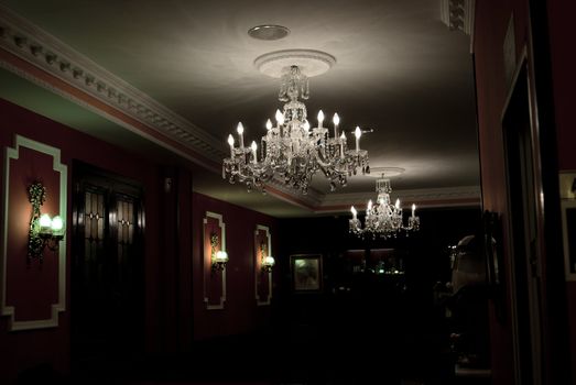 Dark black hall illuminated with crystal antiquarian chandelier and small lamps