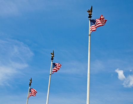 Three American Flags Waving Proudly on Tall Flagpoles