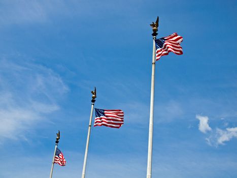 Three American Flags Waving Proudly on Tall Flagpoles