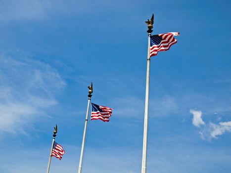 Three American Flags Waving Proudly on Tall Flagpoles