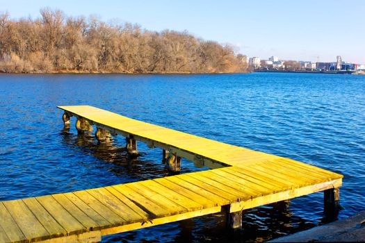 Old wooden pier at the city water reservoir in a fine late autumn day