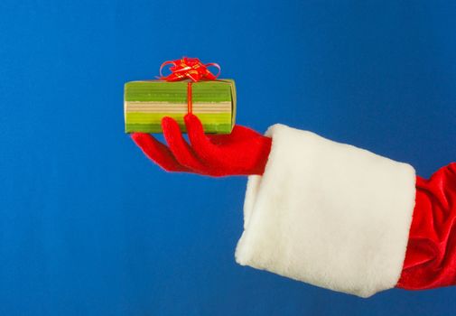 Santa's hand holding a present over blue background