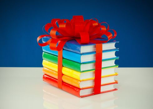 Stack of colorful books tied up with red ribbon