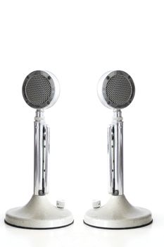 two retro Microphones on white table with its reflection