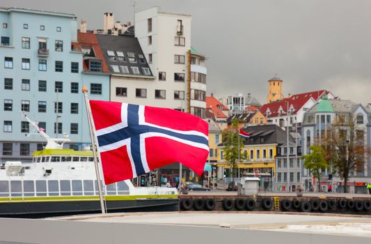 Harbor of the city of Bergen. Focus on norwegian flag. Summer scandinavian weather.