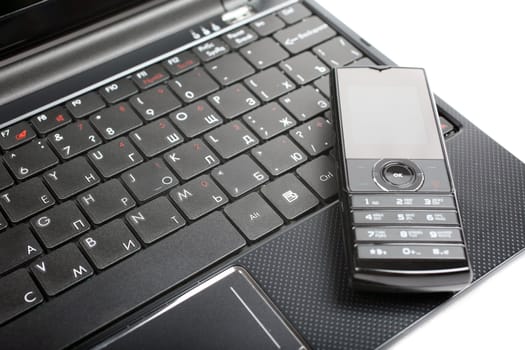 Mobile phone laying on notebook isolated on white background.