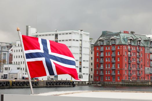 Harbor of the city of Bergen. Focus on norwegian flag. Summer scandinavian weather.