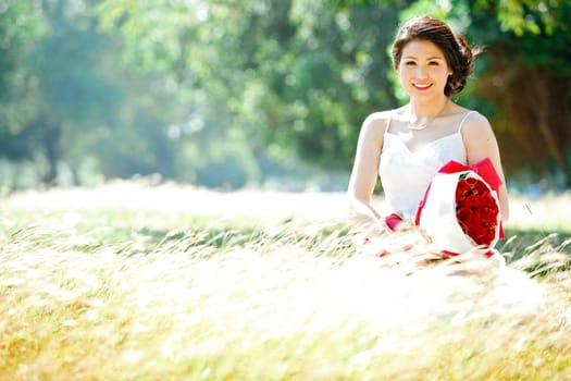 portrait of beautiful bride with rose bouquet on meadows field