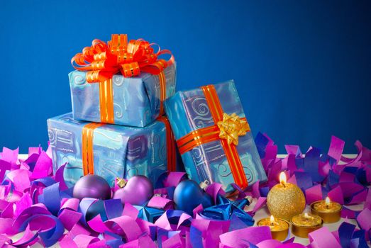 Christmas gifts and candles over blue background