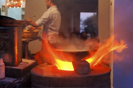Roadside chef cooking up a flaming curry in Jammu Kashmir of a tandoor oven stove, horizontal  landscape wrip copy space and crop margins