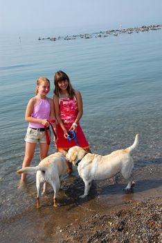 Two girls playing with dogs on a beach