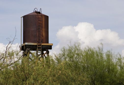 Rusty water tower with a storm cloud in the background.