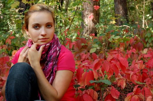 Thoughtful girl sitting in colorful autumn forest