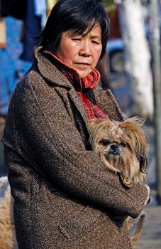 Chinese woman holding her dog in Shanghai street