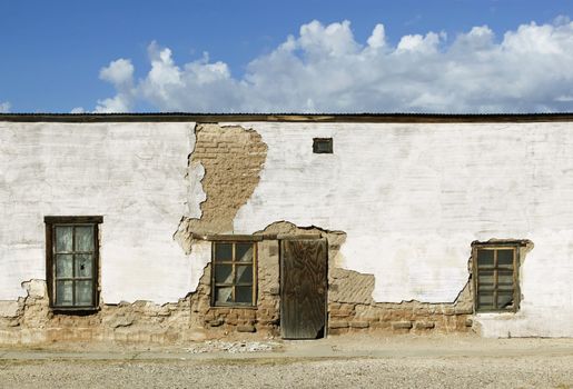 Boarded and abandoned adobe building with a door and windows.