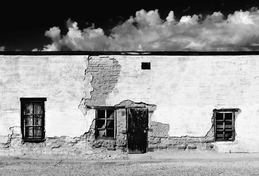 Boarded and abandoned adobe building with a door and windows.