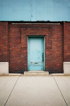 Blue Green Door with Peeling Paint Surrounded by Brick.