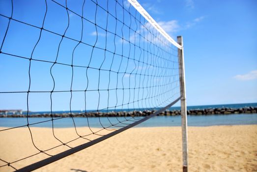 Beach volleyball net in perspective on a sandy beach