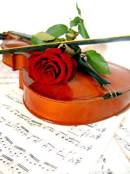 Violin with bow and red rose on music sheet