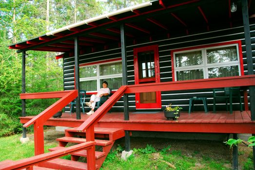 Woman sitting on a deck of log cabin