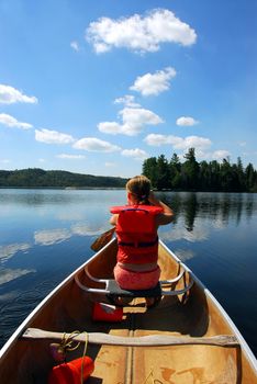 Young girl in canoe paddling on a scenic lake