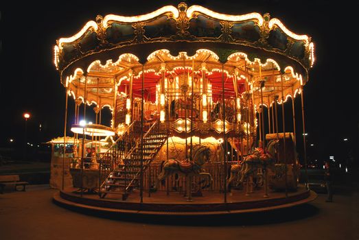 Brightly illuminated traditional carousel in Paris France at night