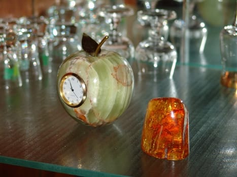 Amber and clock in a stone apple on a glass shelf                               