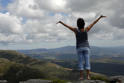 young woman with arms wide open at the mountains