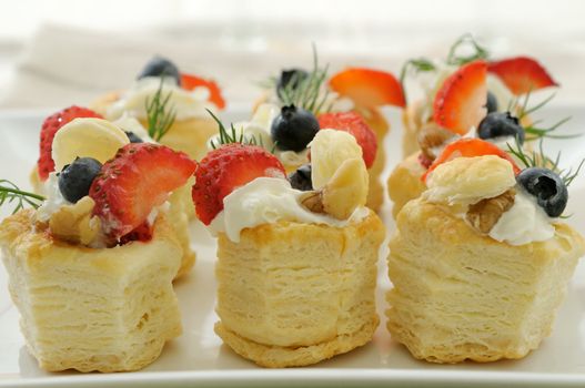 Fruit vol au vent stuffed with whipped cream and topped with strawberry slices and blueberry