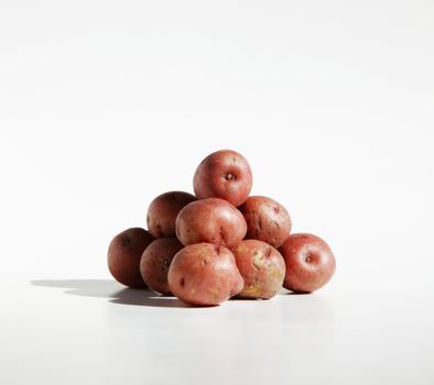 Pile of organic red potatos against a pure white background.