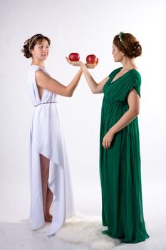 Two ladies in antique dress and two apples on white background
