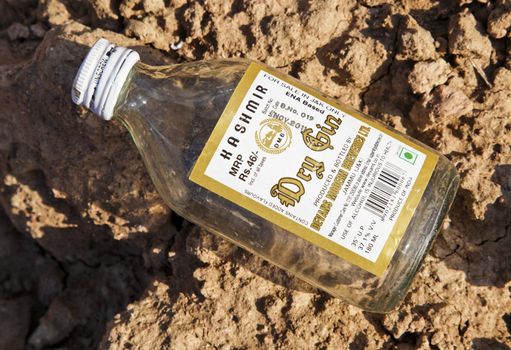 5335, Jammu Kashir, India - December 18, 2011: An empty bottle of Kashmir gin found at the roadside in the no alcohol region of Jammu, landscape or portrait, horizontal or vertical possibilities, crop margins and copy spaces.