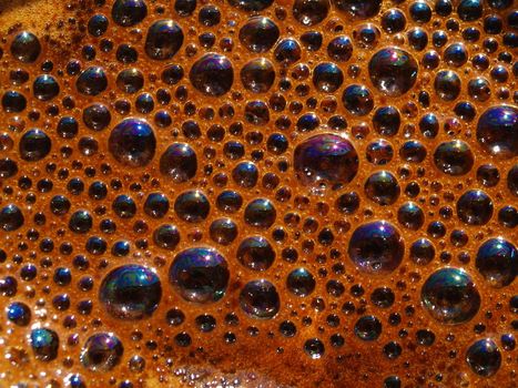 Bubbles and froth on the surface of a fresh brewed pot of pressed coffee.
