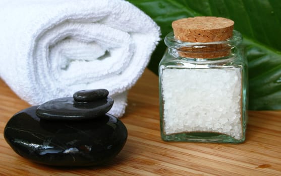 White bath towel, bottle of sea salt and black stones in spa composition

