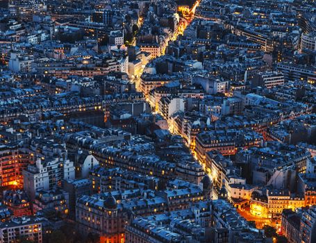 Aerial night view of an illuminated street between crowded buildings in Paris.