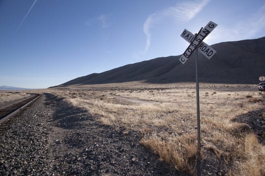 Railroad crossing tracks in the desert with blue skies.