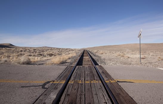 Railroad crossing tracks in the desert with blue skies.